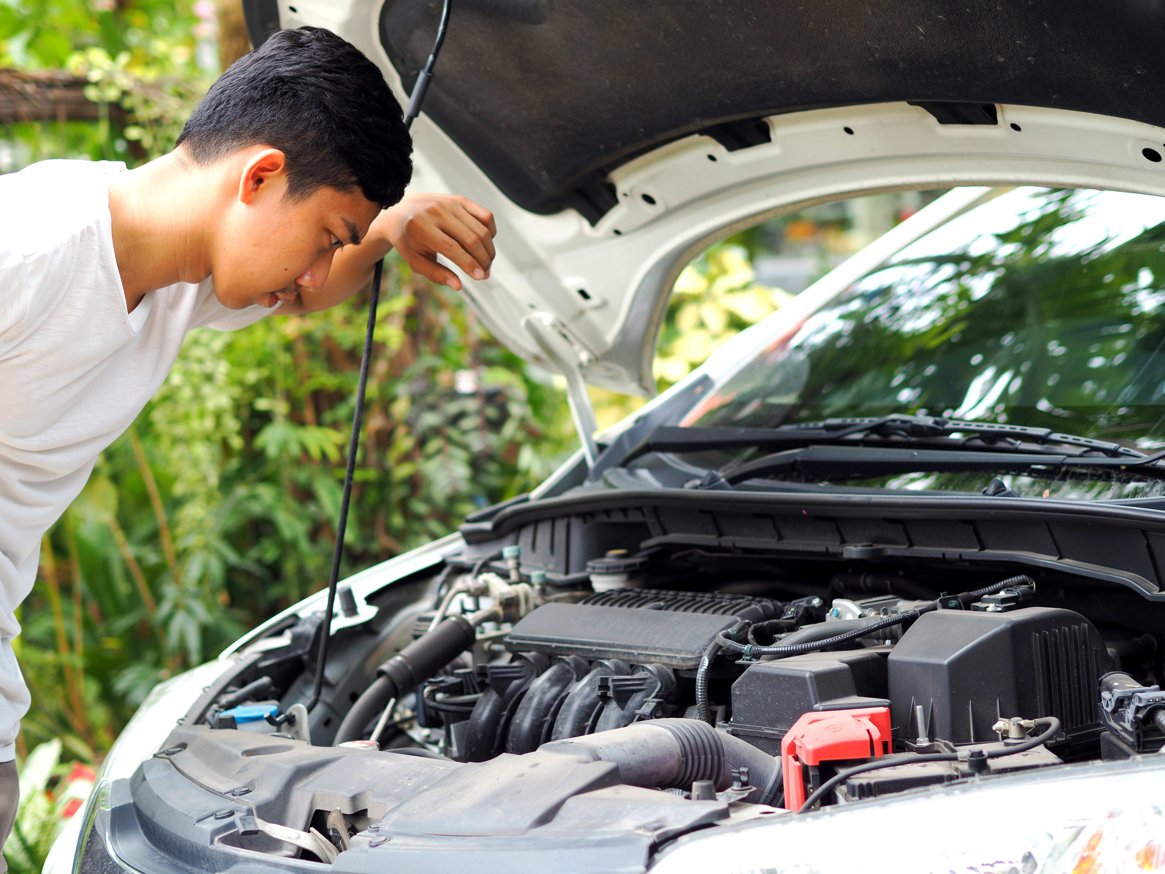 Man in White Tshirt Looking at Engine for Car Maintenance