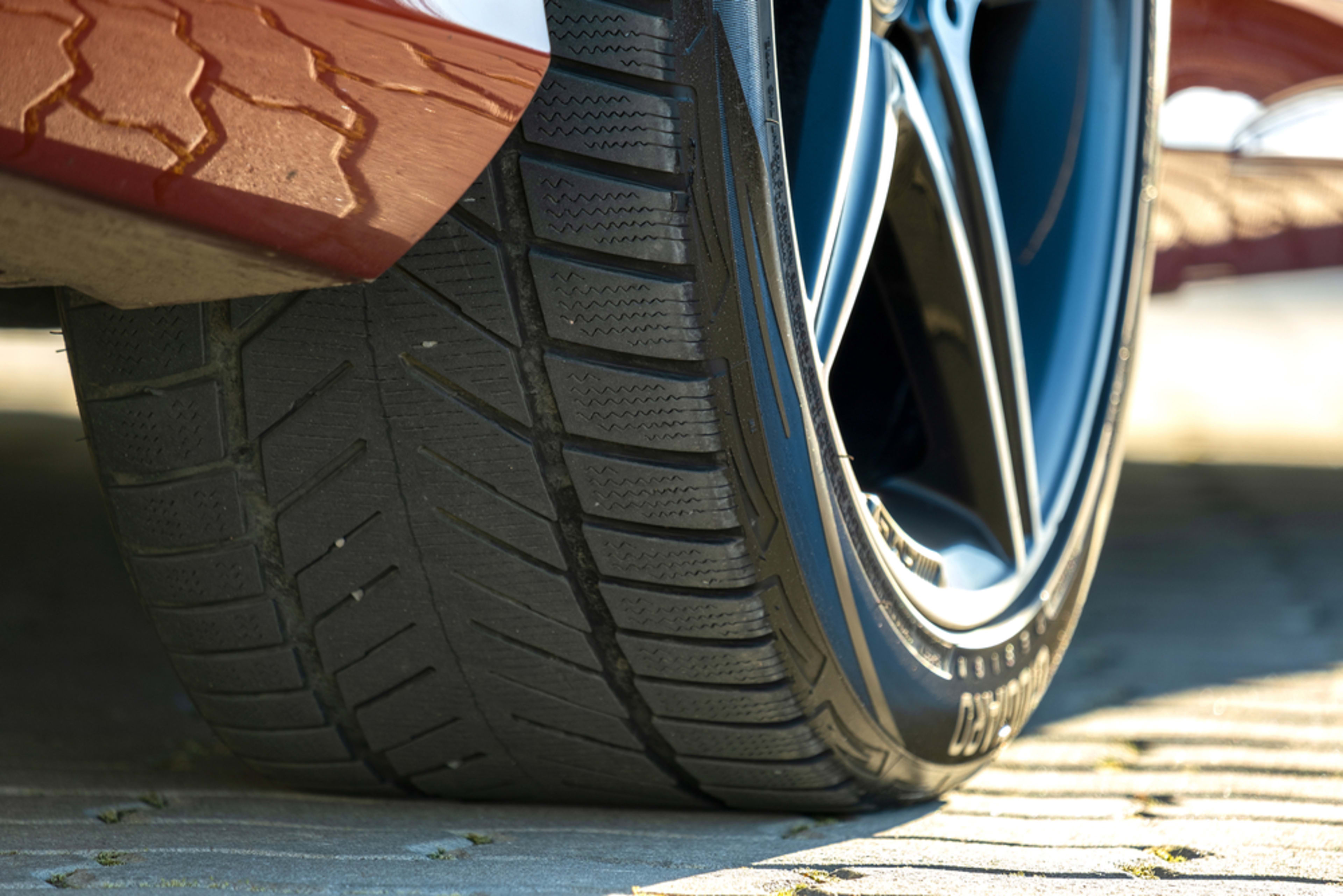 A closeup of a properly installed tire on a red car, showcasing its tread.