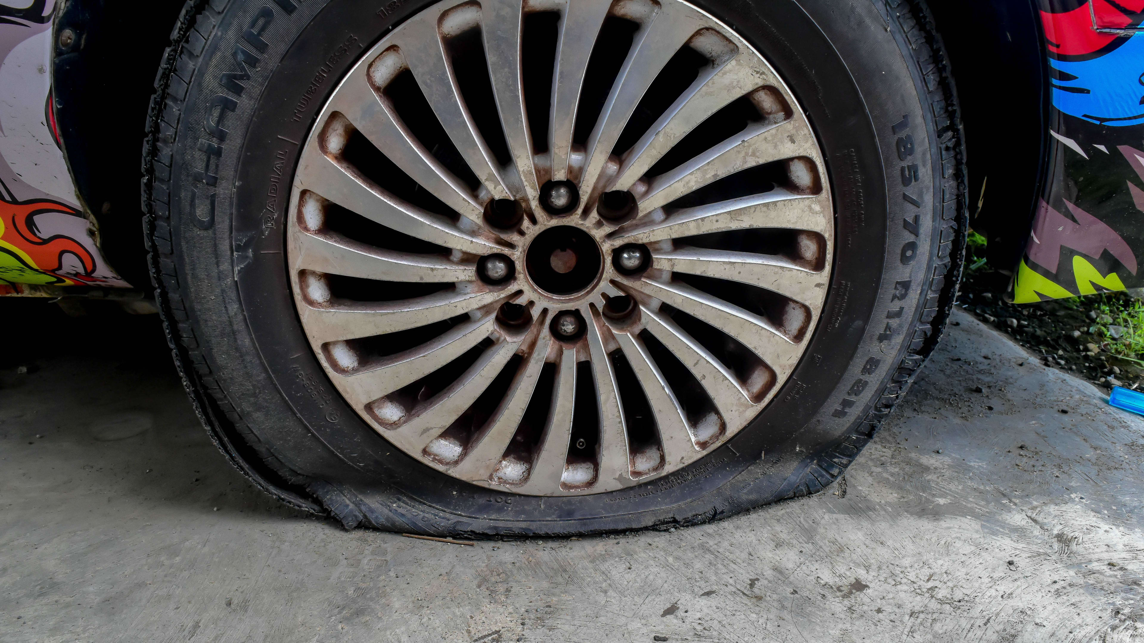 A flat tire on a passenger car with a unique paint job.