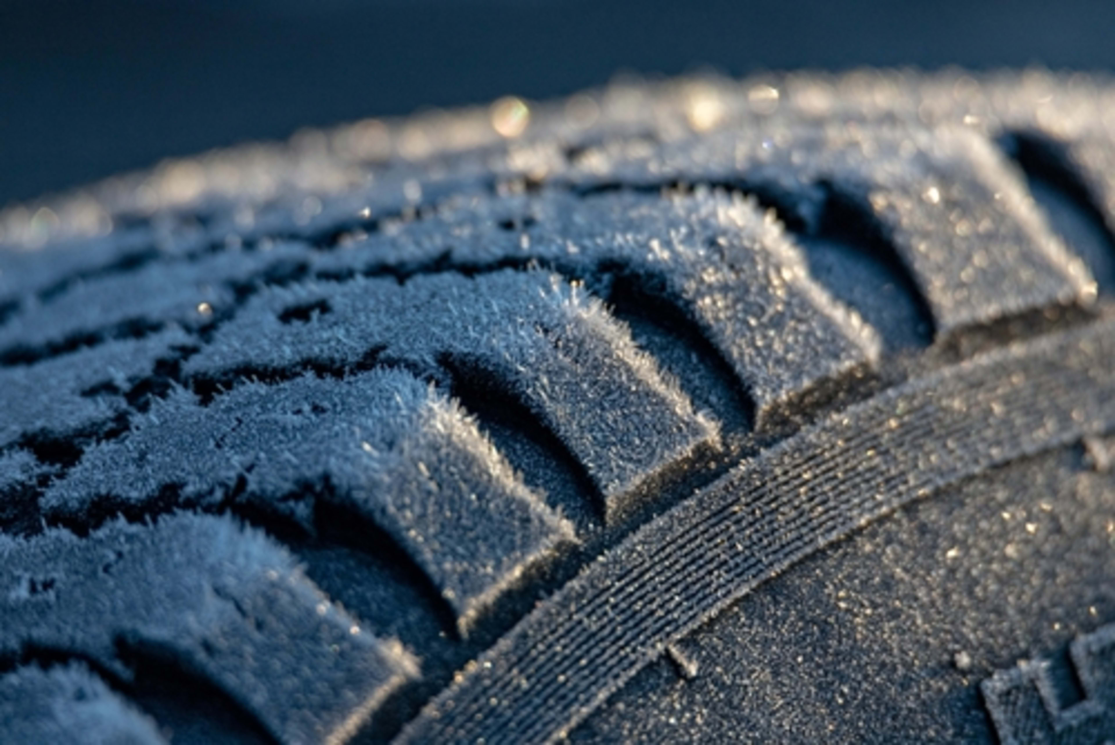 Close-up of an icy tire and its tread and some sidewall.