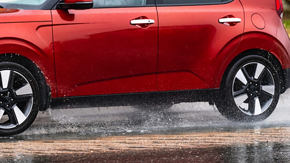 A red SUV driving on a wet road.