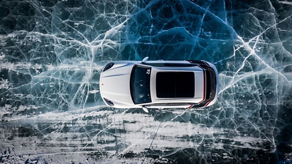 White Porsche 911 driving on an iced over lake.