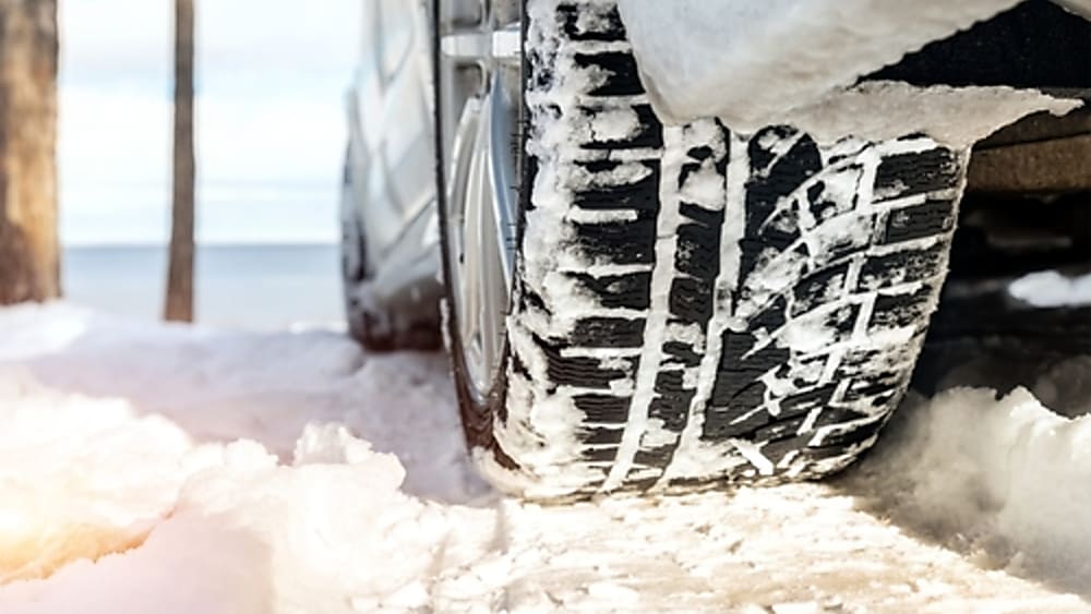 Close-up of a winter tire driving safely down a snowy dirt road