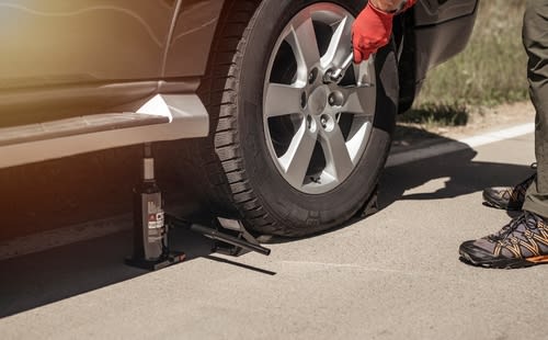 Safely checking a tire with the proper jack and tools.