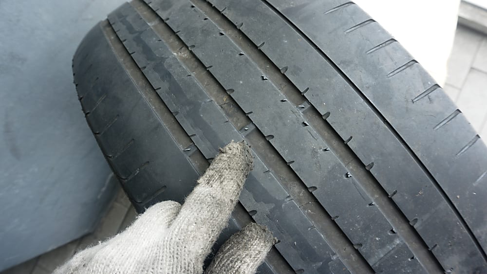 Mechanic pointing to a tire's tread wear bars.