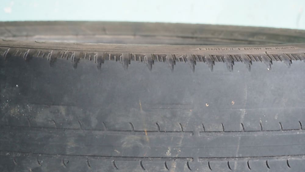 A tire wearing unevenly and balding more intensely on side of the tread.