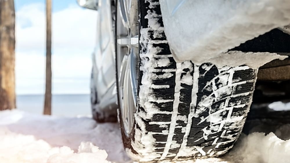 Close-up of a winter tire driving safely down a snowy dirt road